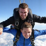 Portrait of a skydiving videographer capturing a tandem jump in mid-air.