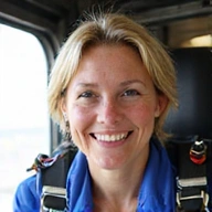 Portrait of Sarah Jenkins, a smiling female skydiving instructor with a parachute in the background.